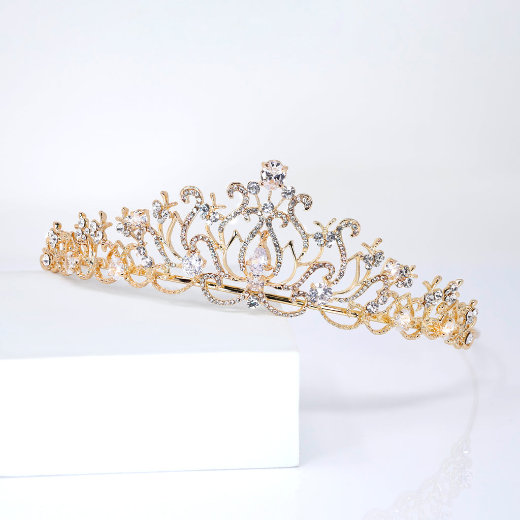 A gold tiara with a decorative design and sparkling gemstones.