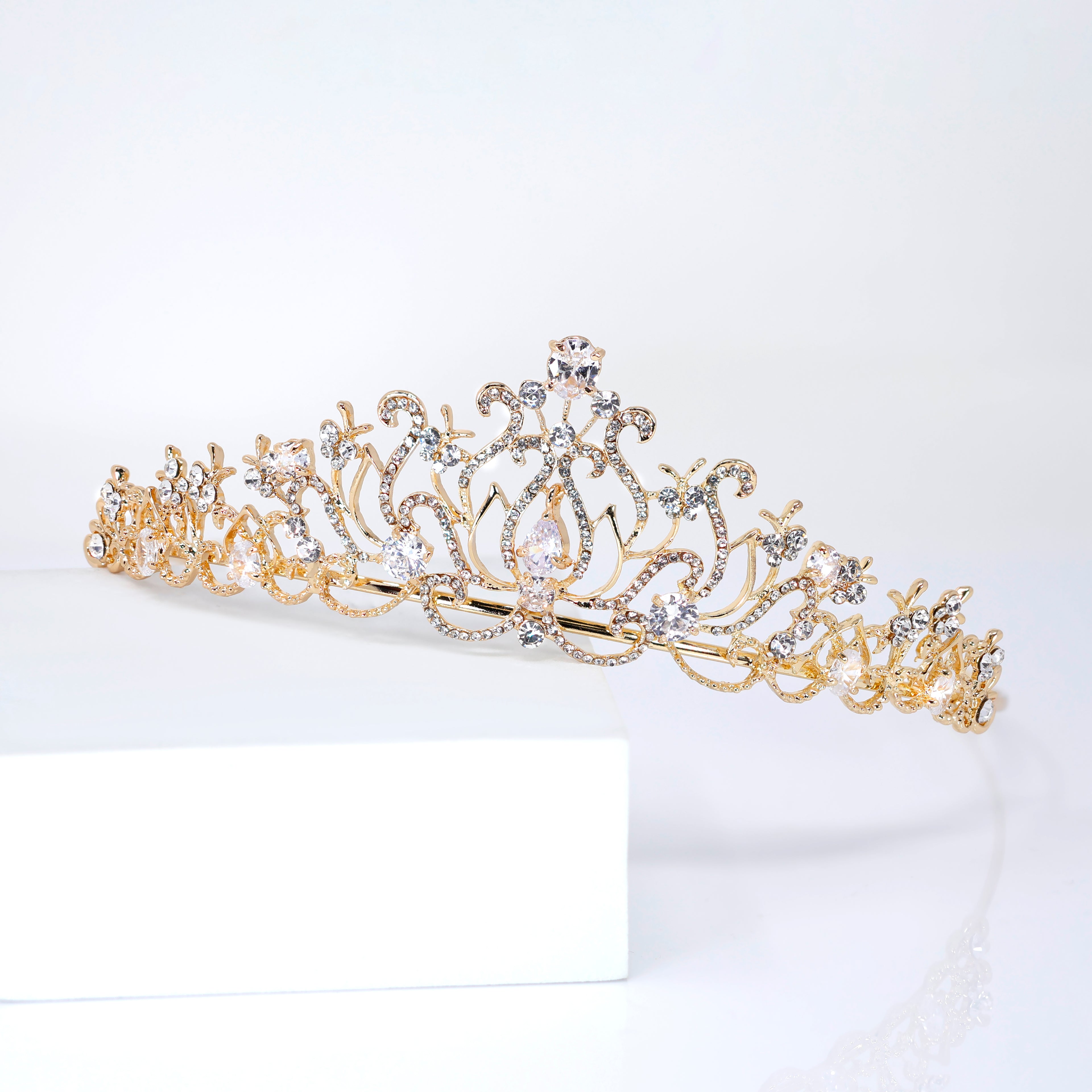 A gold tiara with a decorative design and sparkling gemstones.