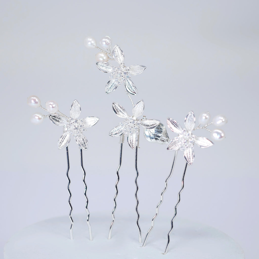 a group of silver hair clips adorned with white flowers, arranged in a visually appealing manner.