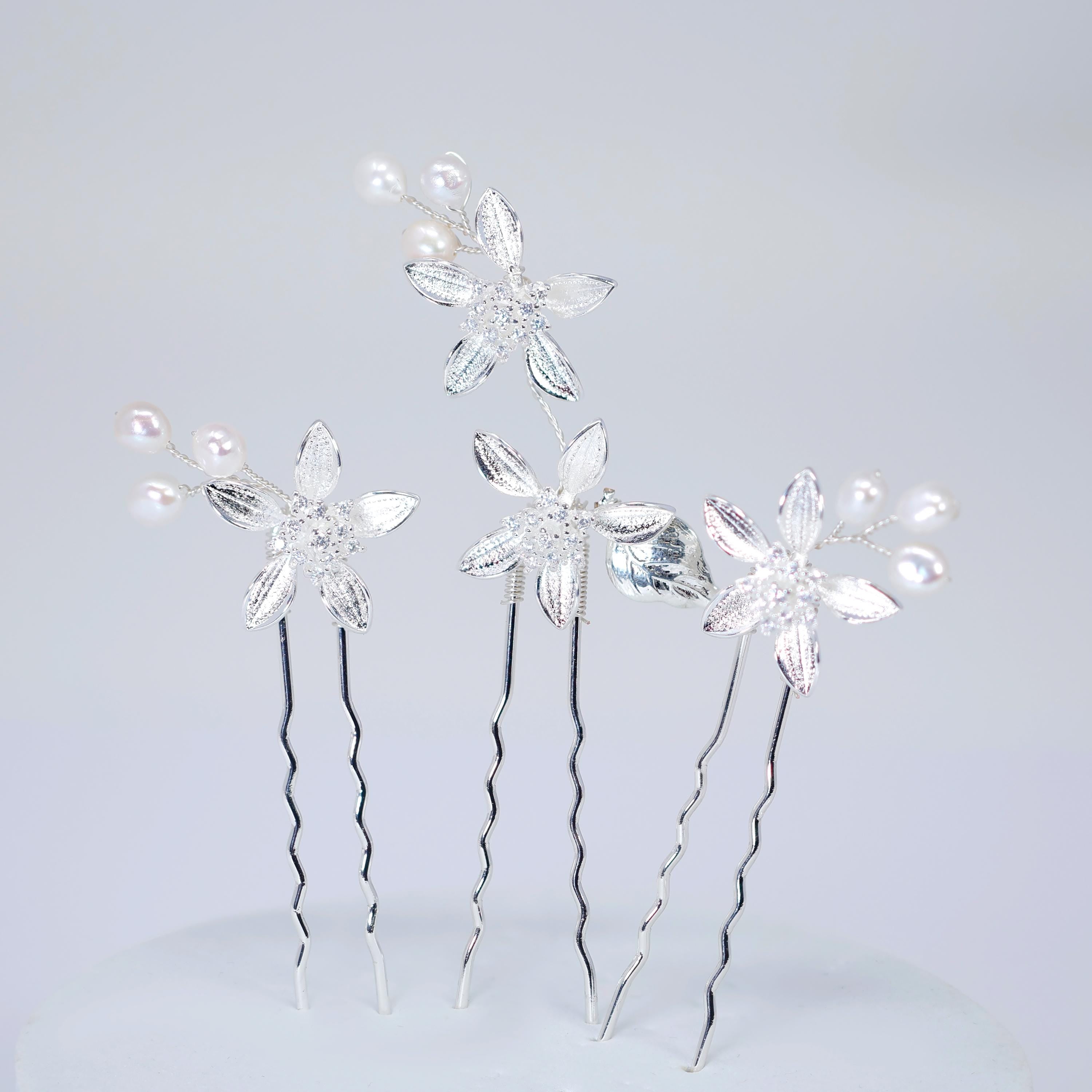 a group of silver hair clips adorned with white flowers, arranged in a visually appealing manner.