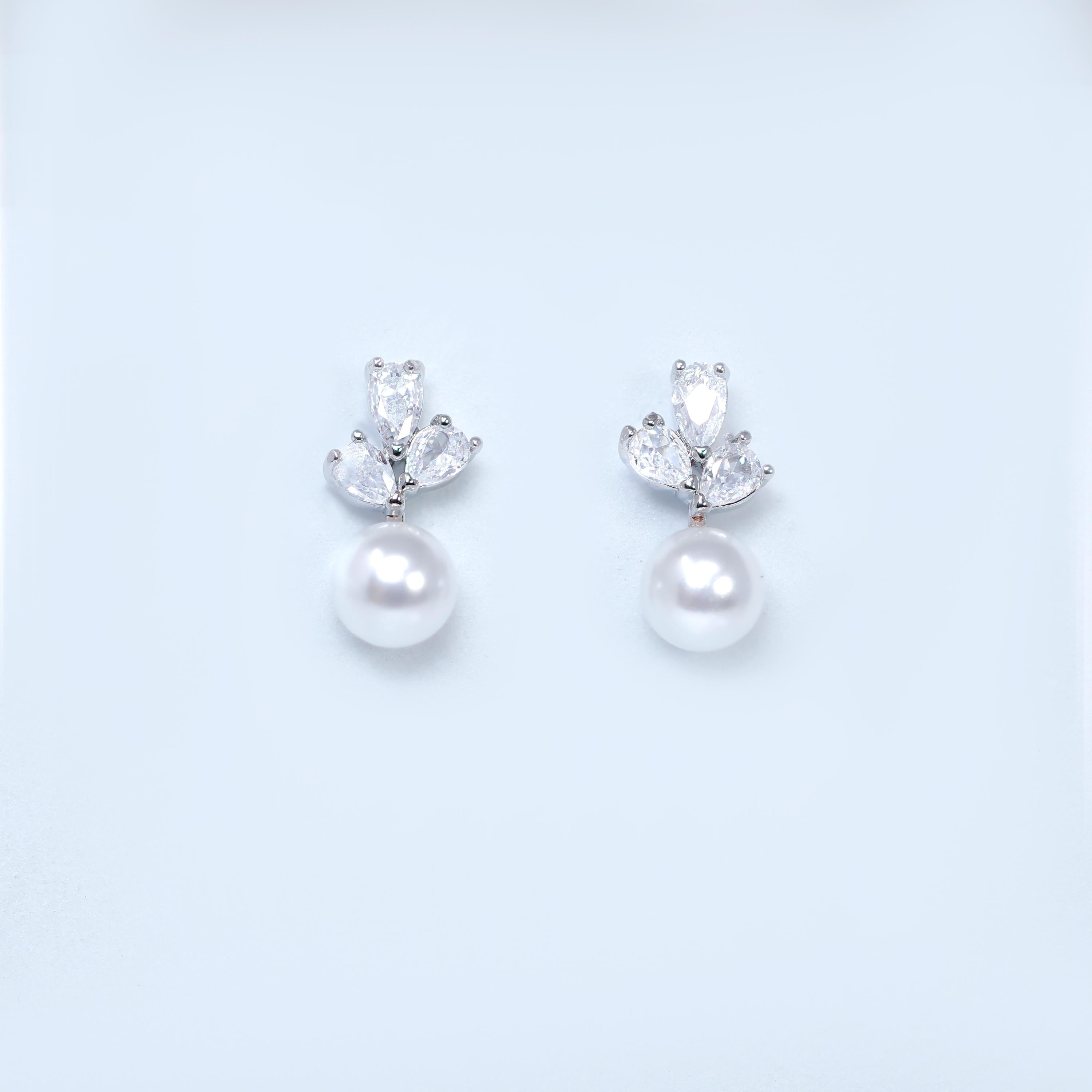 A pair of elegant earrings with a pearl and a crystal embellishment.