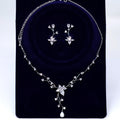 A necklace and earrings set made of white diamonds and silver, displayed on a dark blue velvet background.