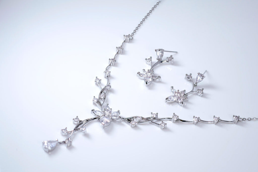 A necklace and earrings with a floral design are displayed against a white background.