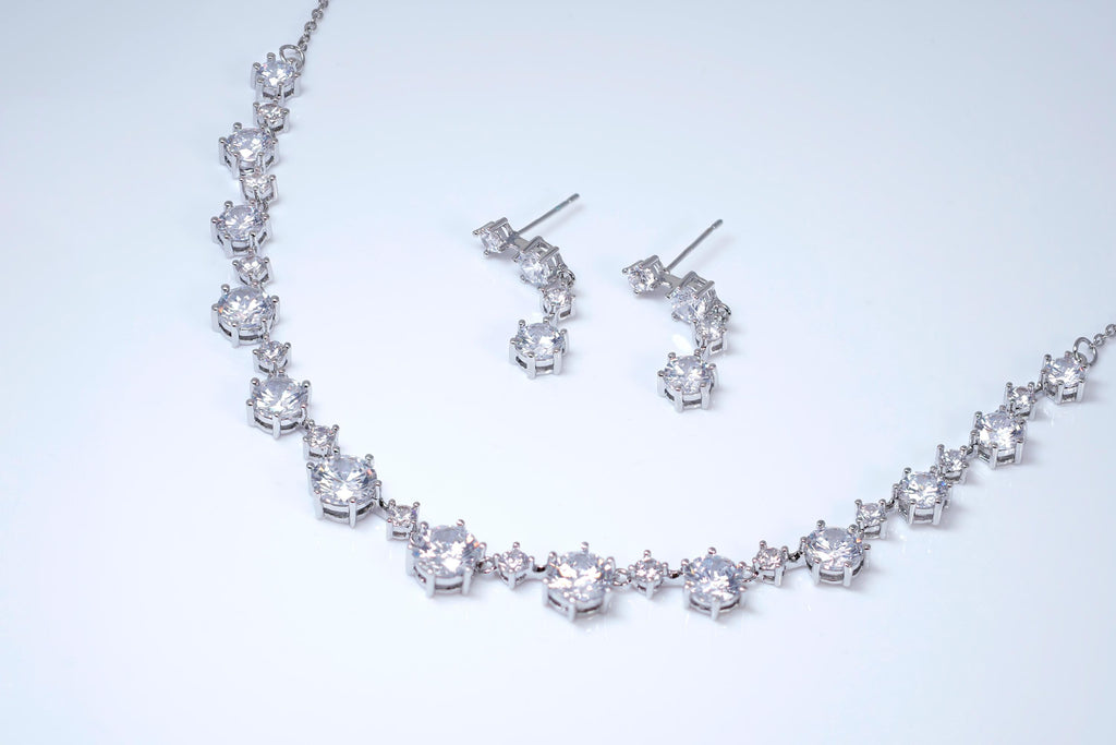A necklace and earrings made of sparkling diamonds are displayed against a white background.