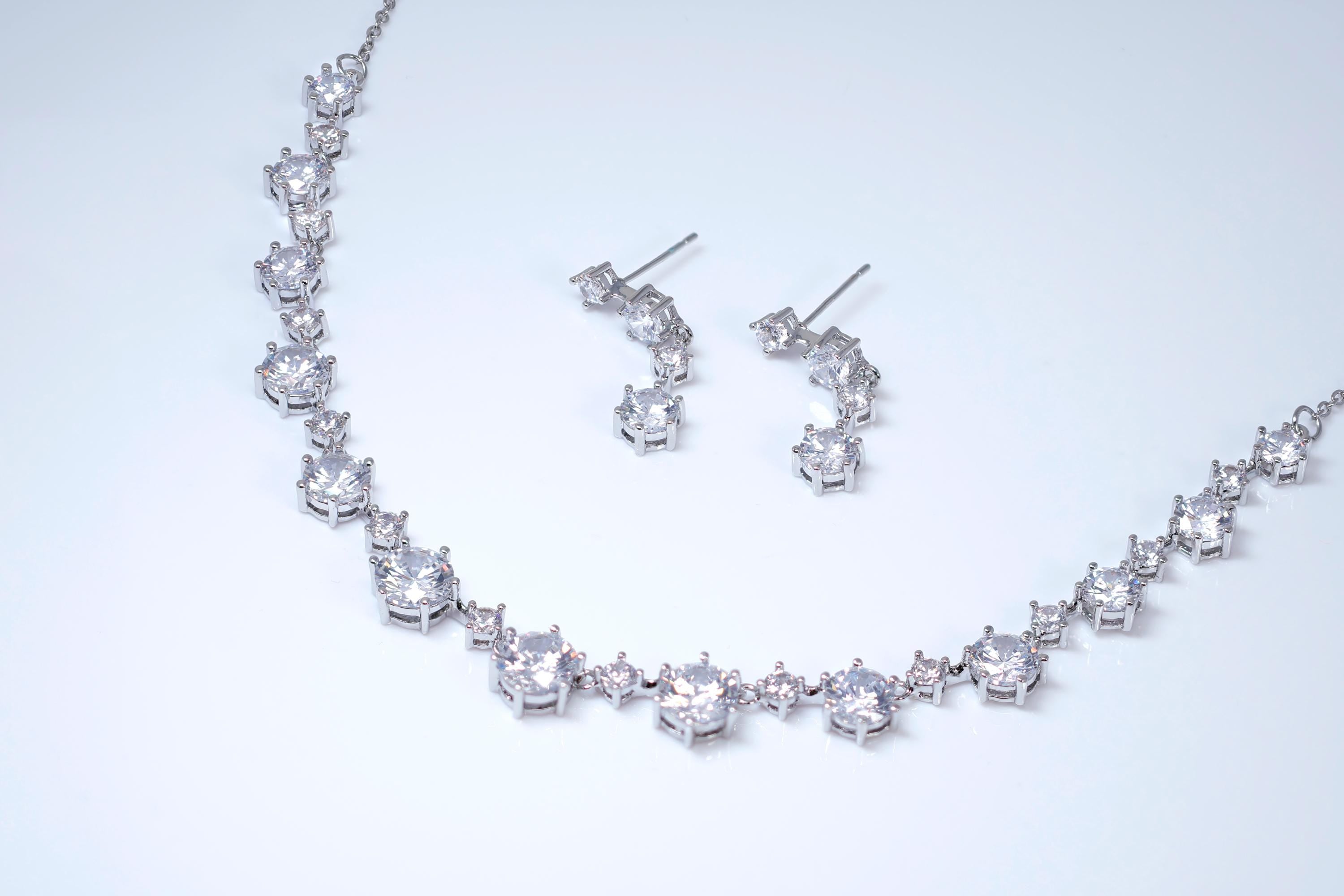 A necklace and earrings made of sparkling diamonds are displayed against a white background.