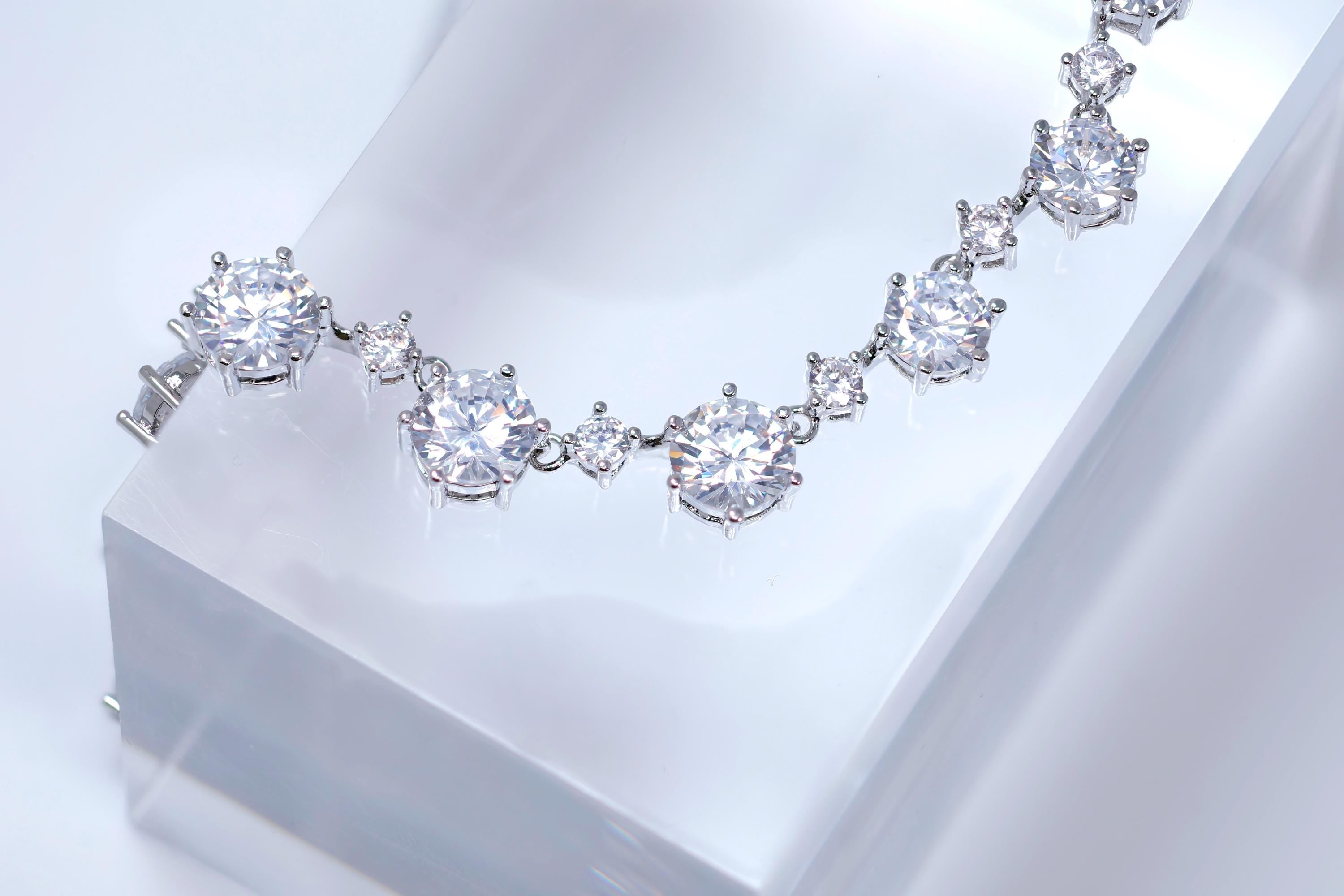 A necklace with numerous large, clear diamonds set in a silver-toned metal.