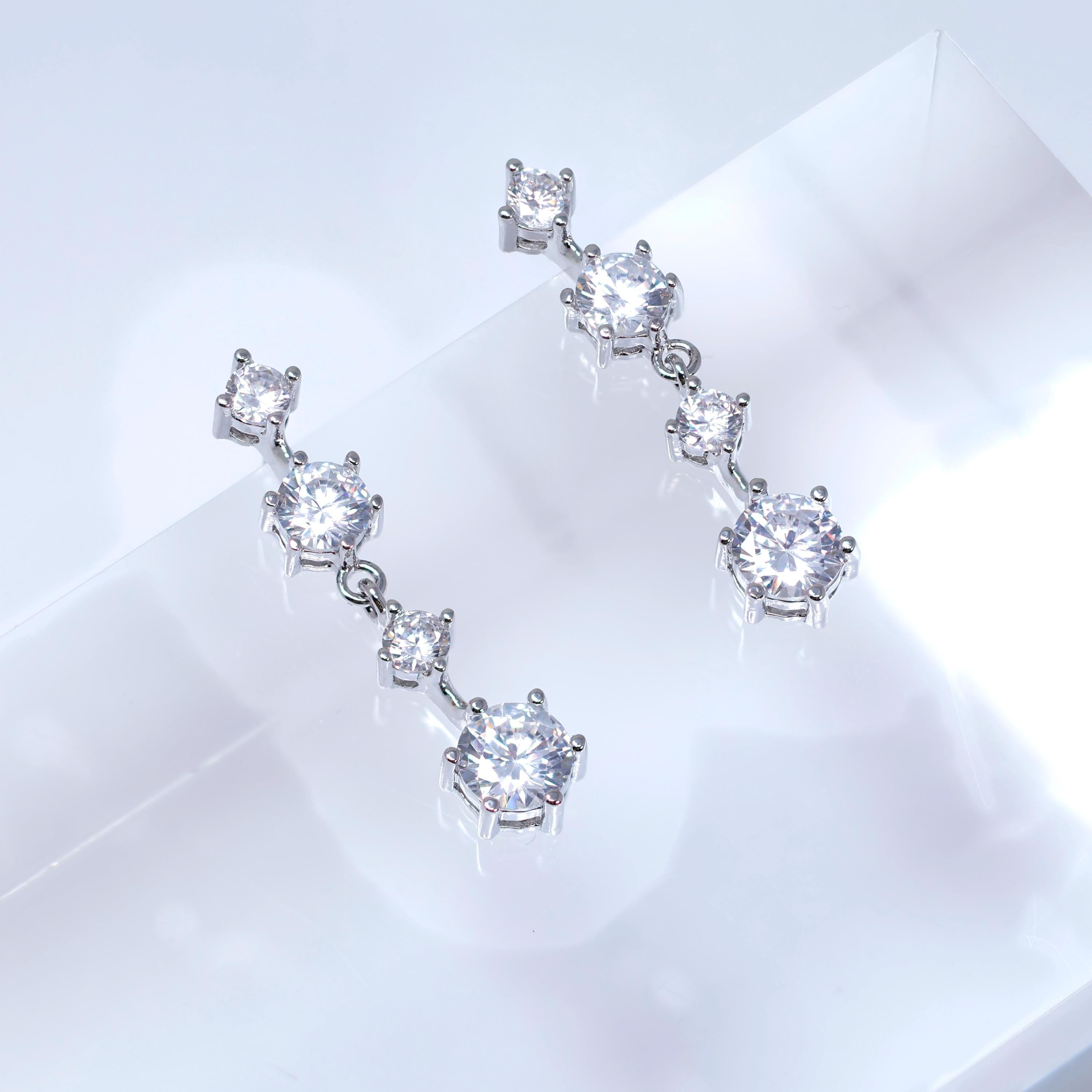 A pair of elegant diamond earrings with multiple small diamonds hanging from a central rod.