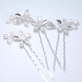 a collection of silver hair pins with flower-shaped designs, including pearls and leaves, arranged on a white background.