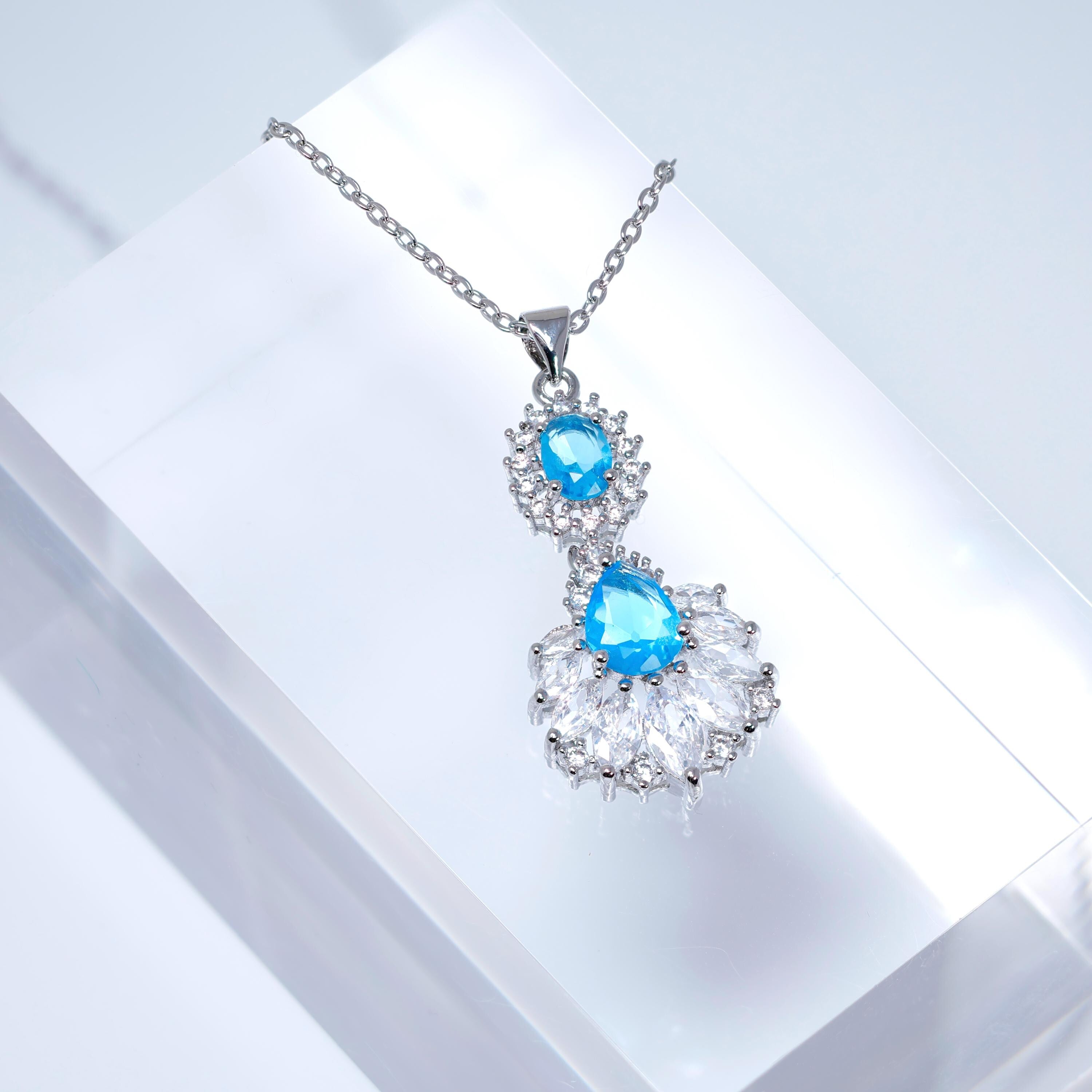 A necklace with a pendant featuring blue gemstones and a floral design.