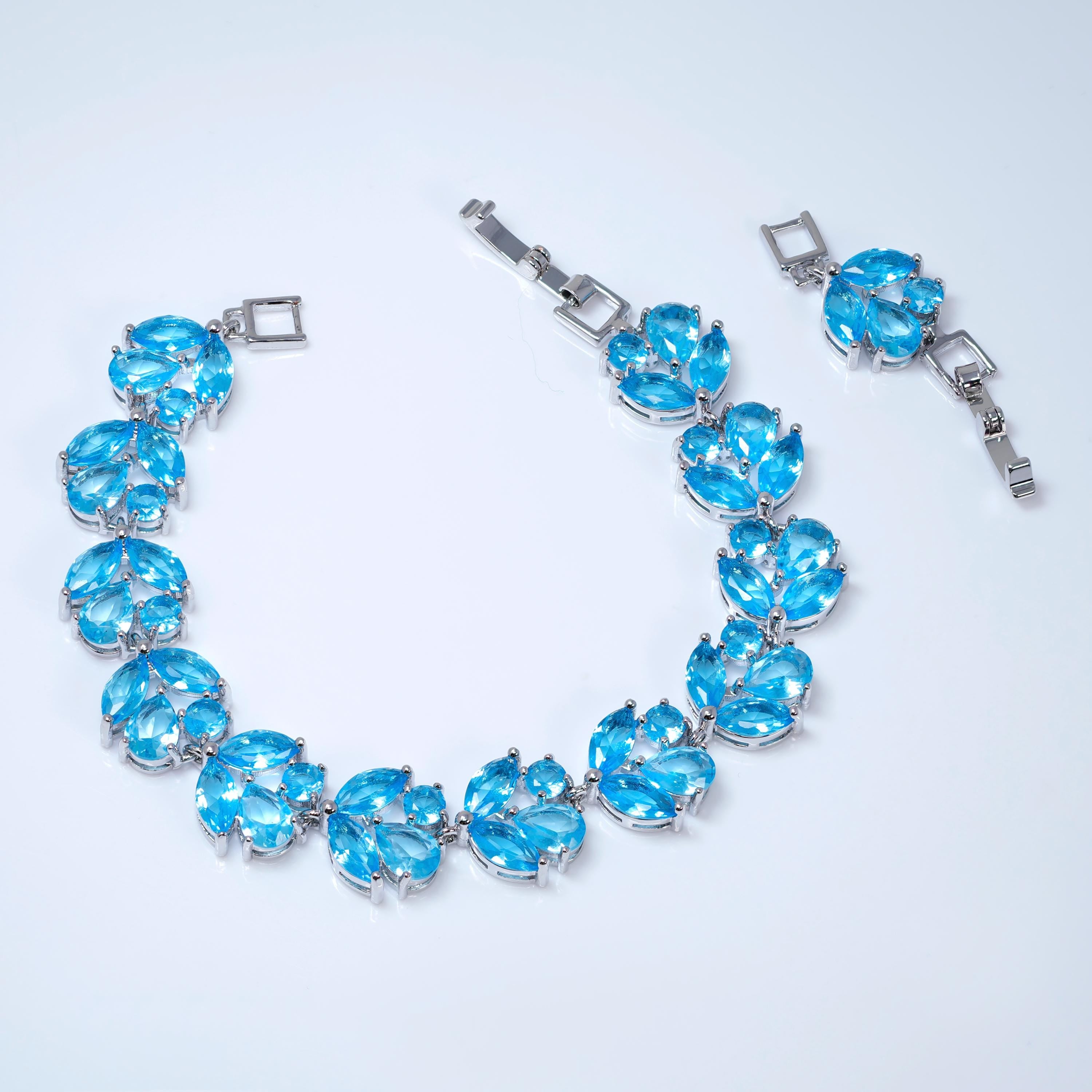 A silver necklace with blue gemstone pendants is displayed on a white background.