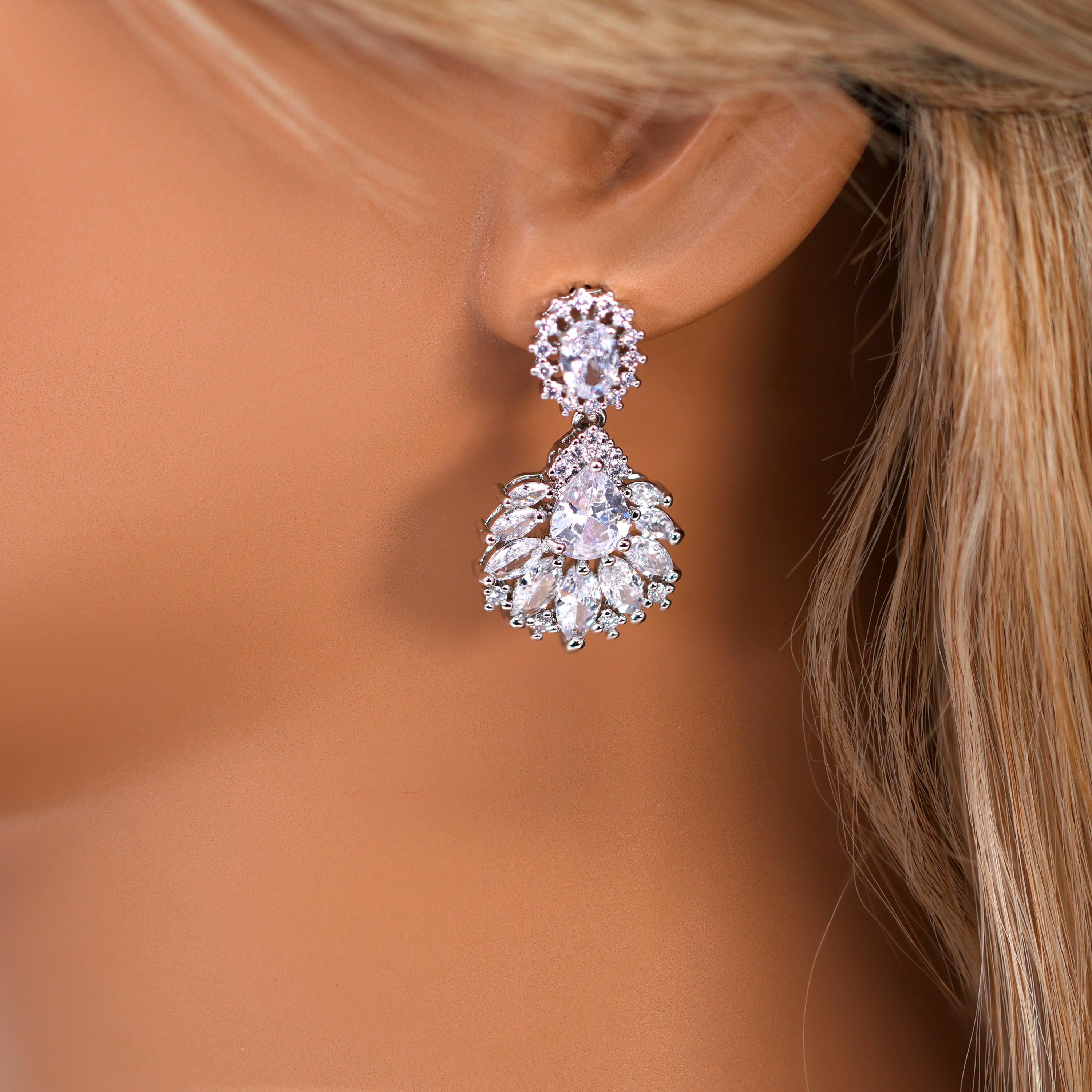 A close-up of a person's ear wearing a pair of elegant diamond earrings.