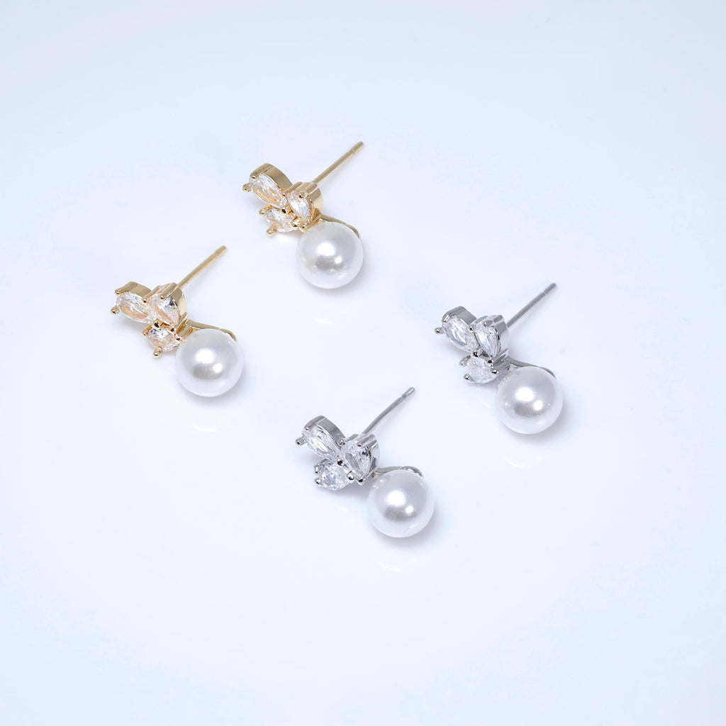 A pair of earrings with white pearls and gold or silver gemstone accents.