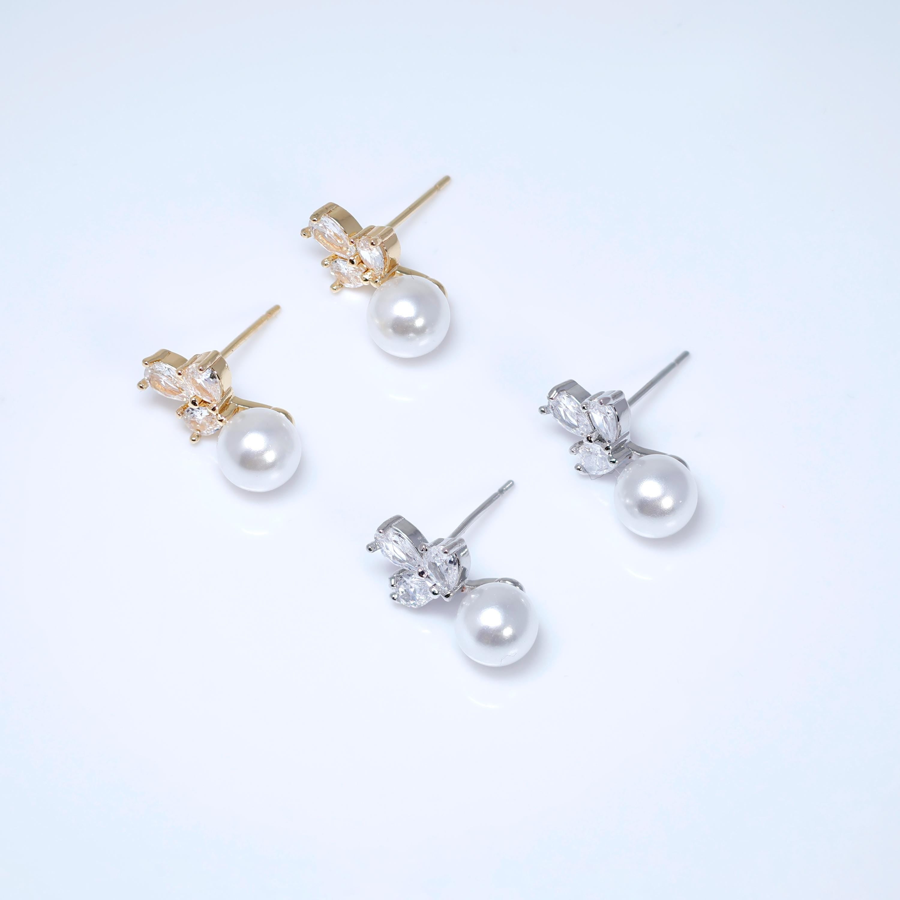 A pair of earrings with white pearls and gold or silver gemstone accents.