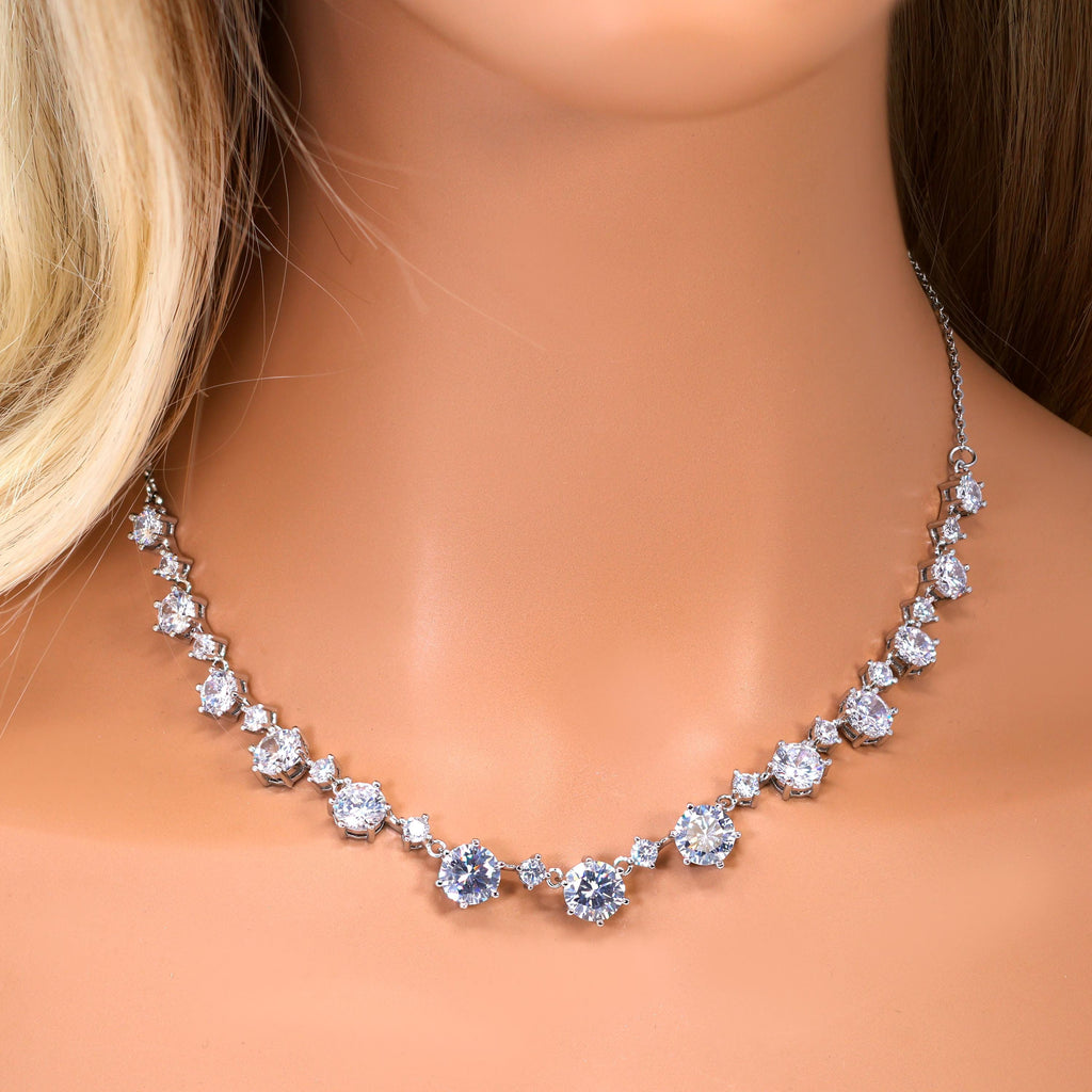 A close-up of a woman's neck wearing a necklace with a row of sparkling diamonds.
