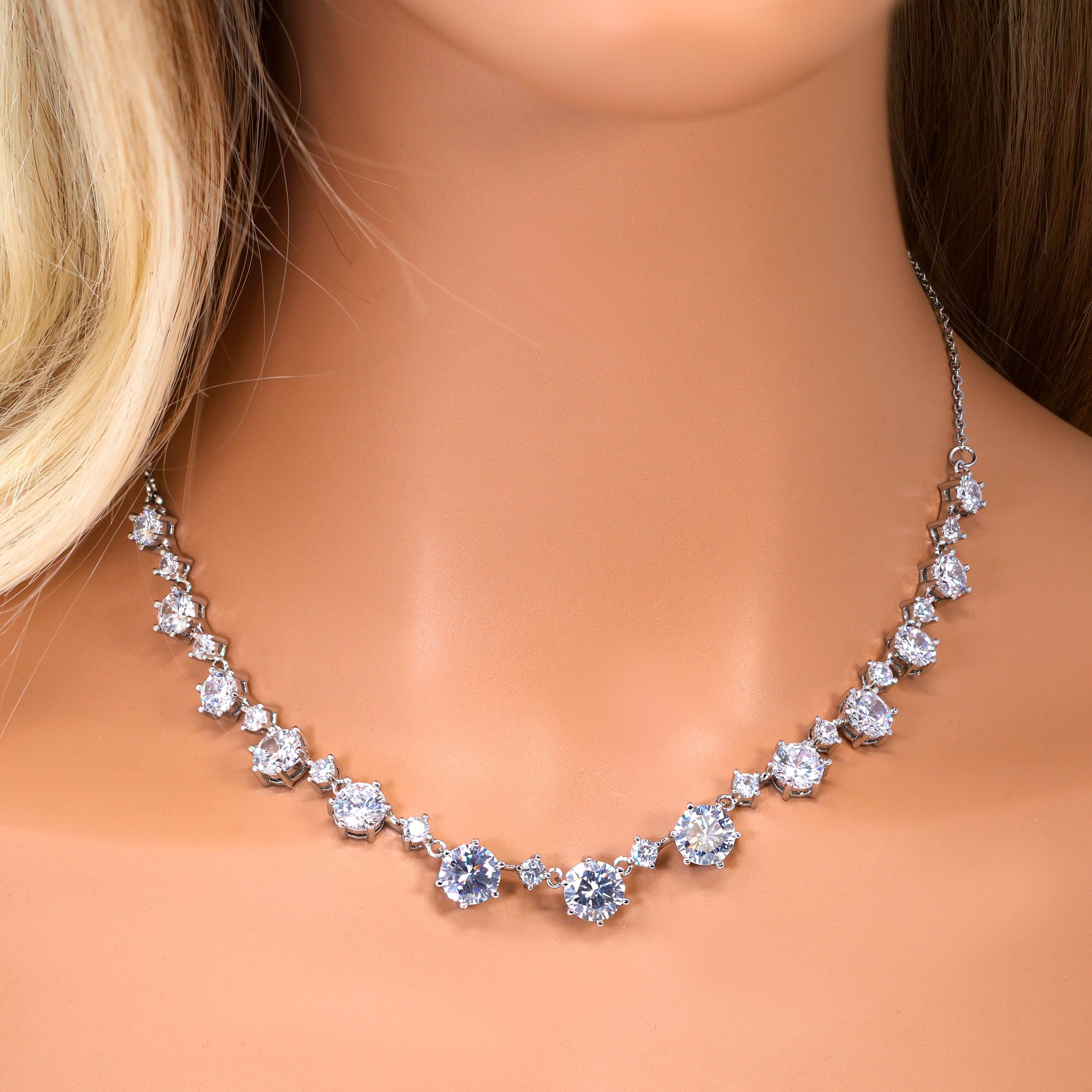 A close-up of a woman's neck wearing a necklace with a row of sparkling diamonds.
