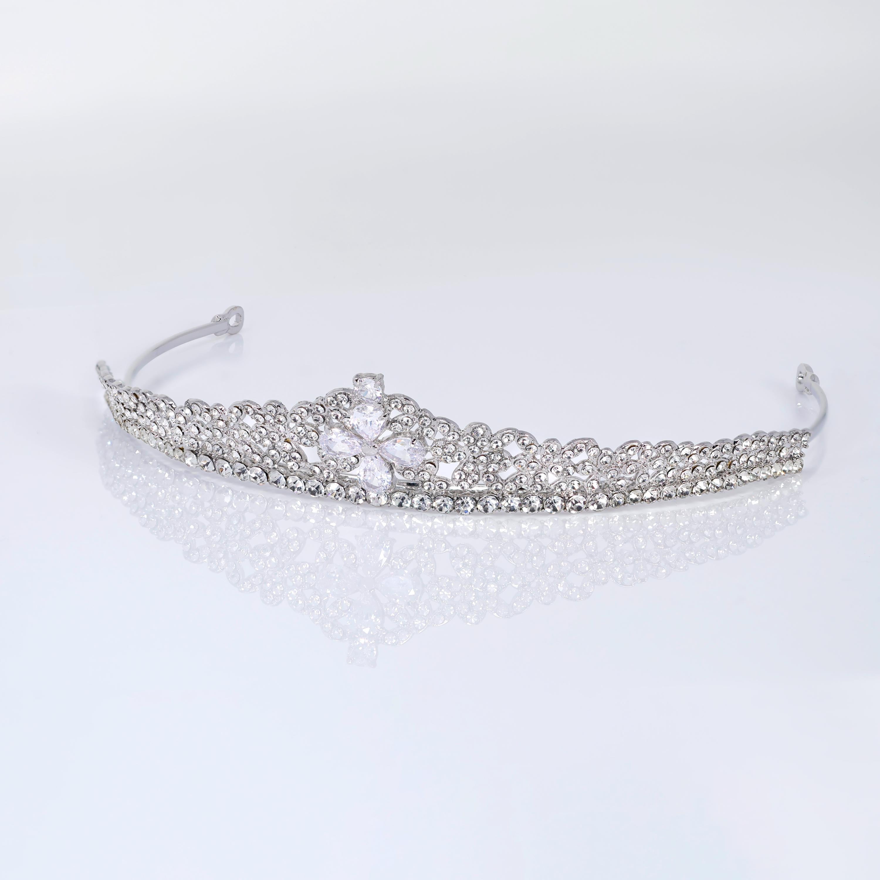 A silver tiara with a large crystal or gemstone at the center, resting on a white surface.