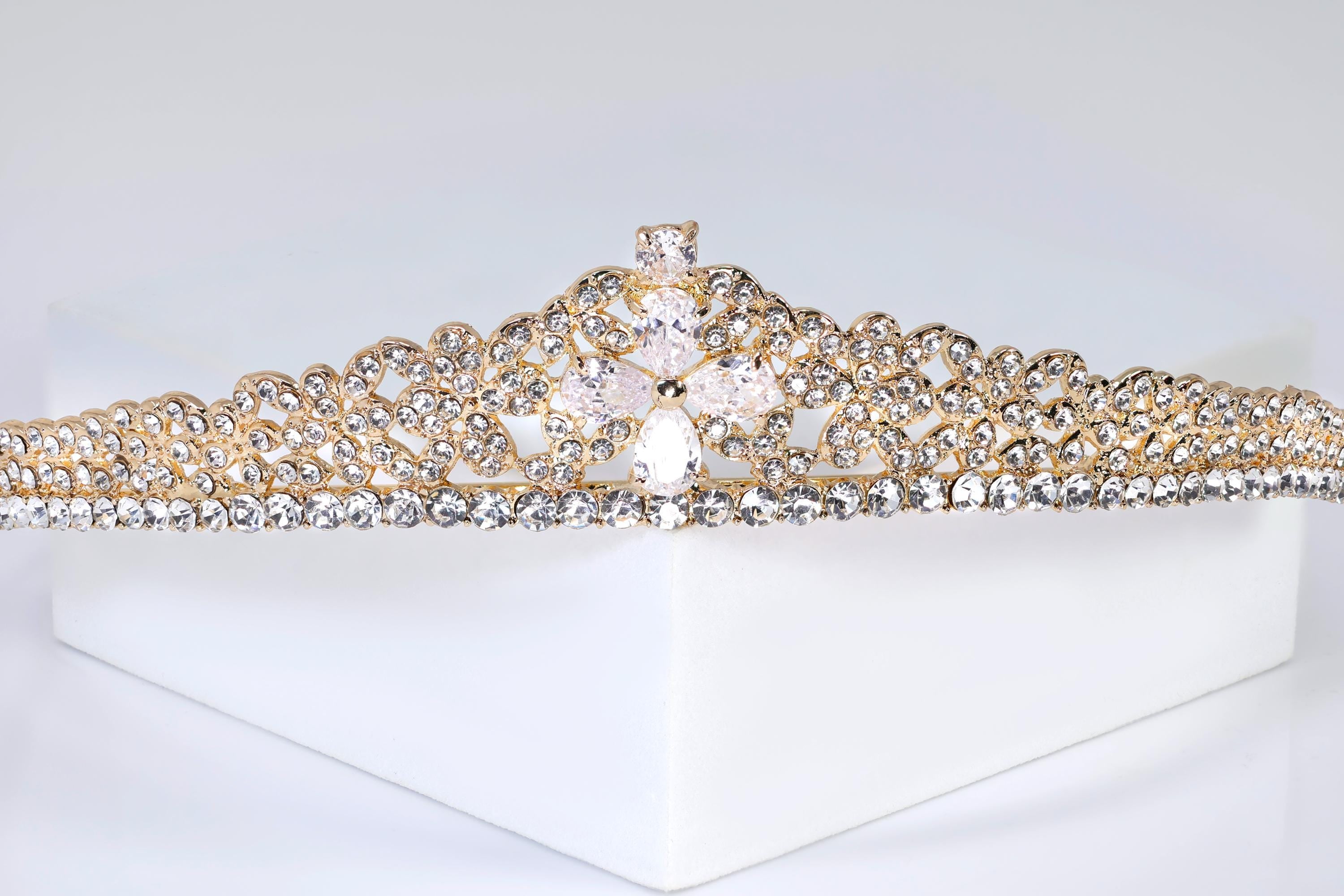 A close-up view of a gold and diamond-encrusted tiara against a white background.